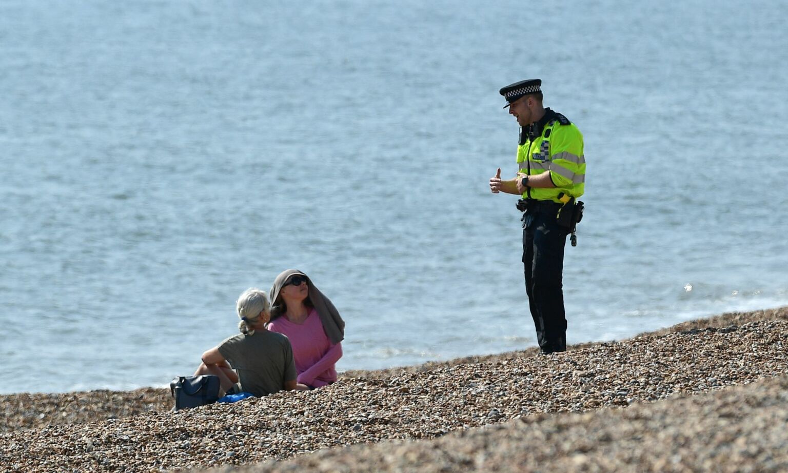 A police officer asks members of the public to leave the beach in Brighton, England, 10 April 2020.