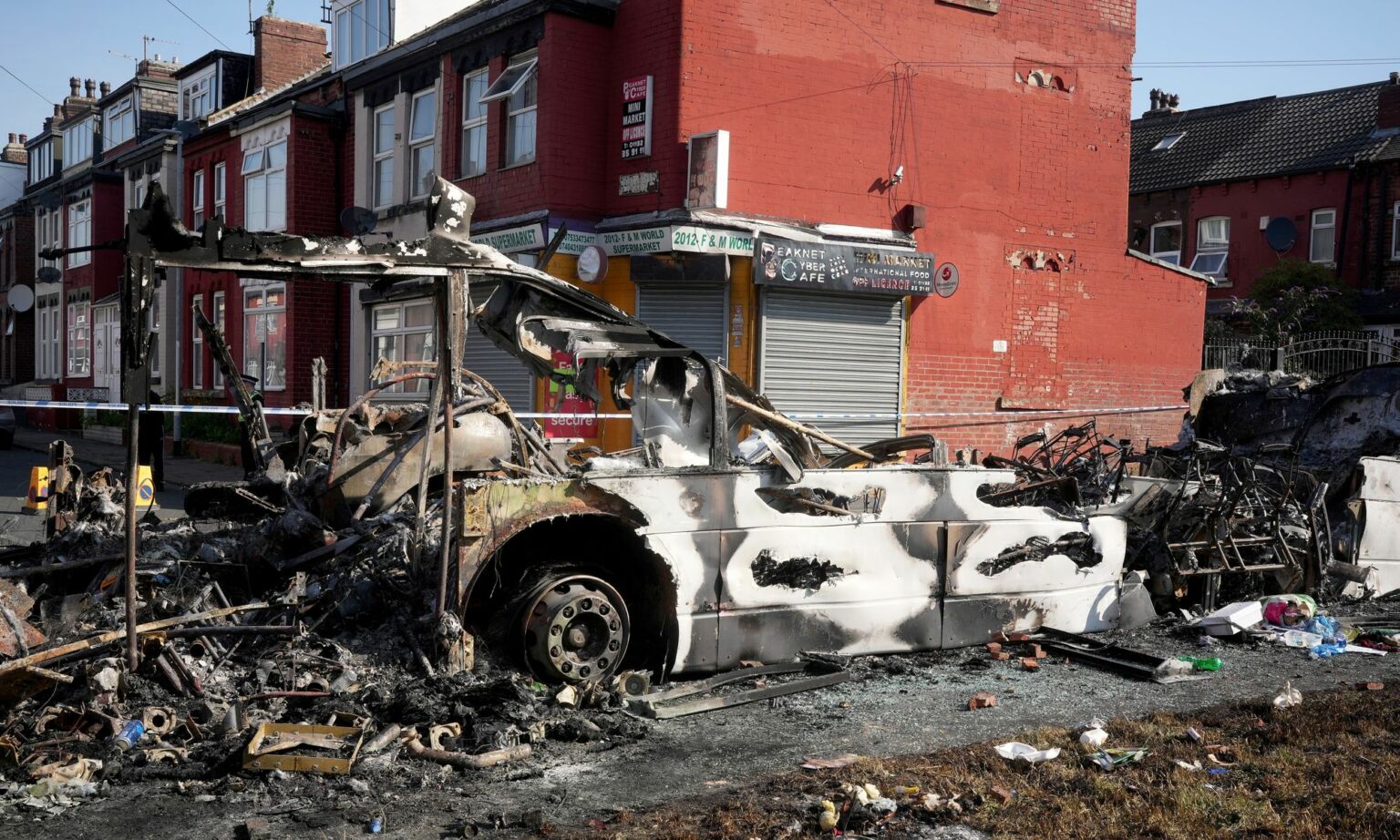 Police tape cordons off the remains of a burnt-out bus following riots in the Harehills area of Leeds, 19 July  2024.