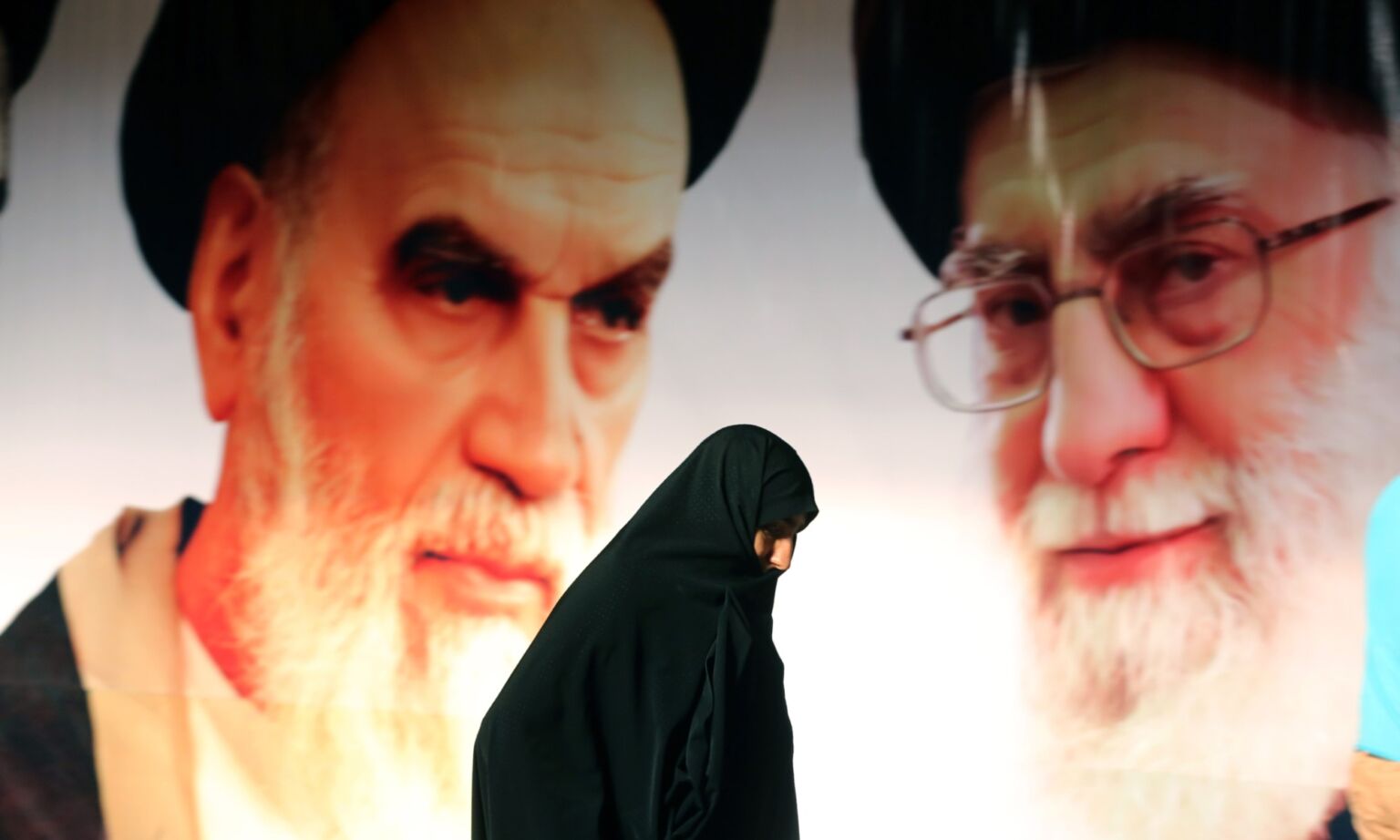 An Iranian woman walks past a giant poster showing supreme leader, Ayatollah Ali Khamenei and Ayatollah Ruhollah Khomeini, Tehran, 2015
