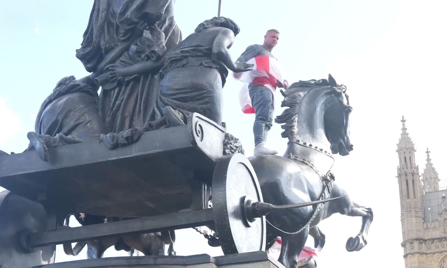 A protester climbs a statue on the corner of Westminster Bridge.